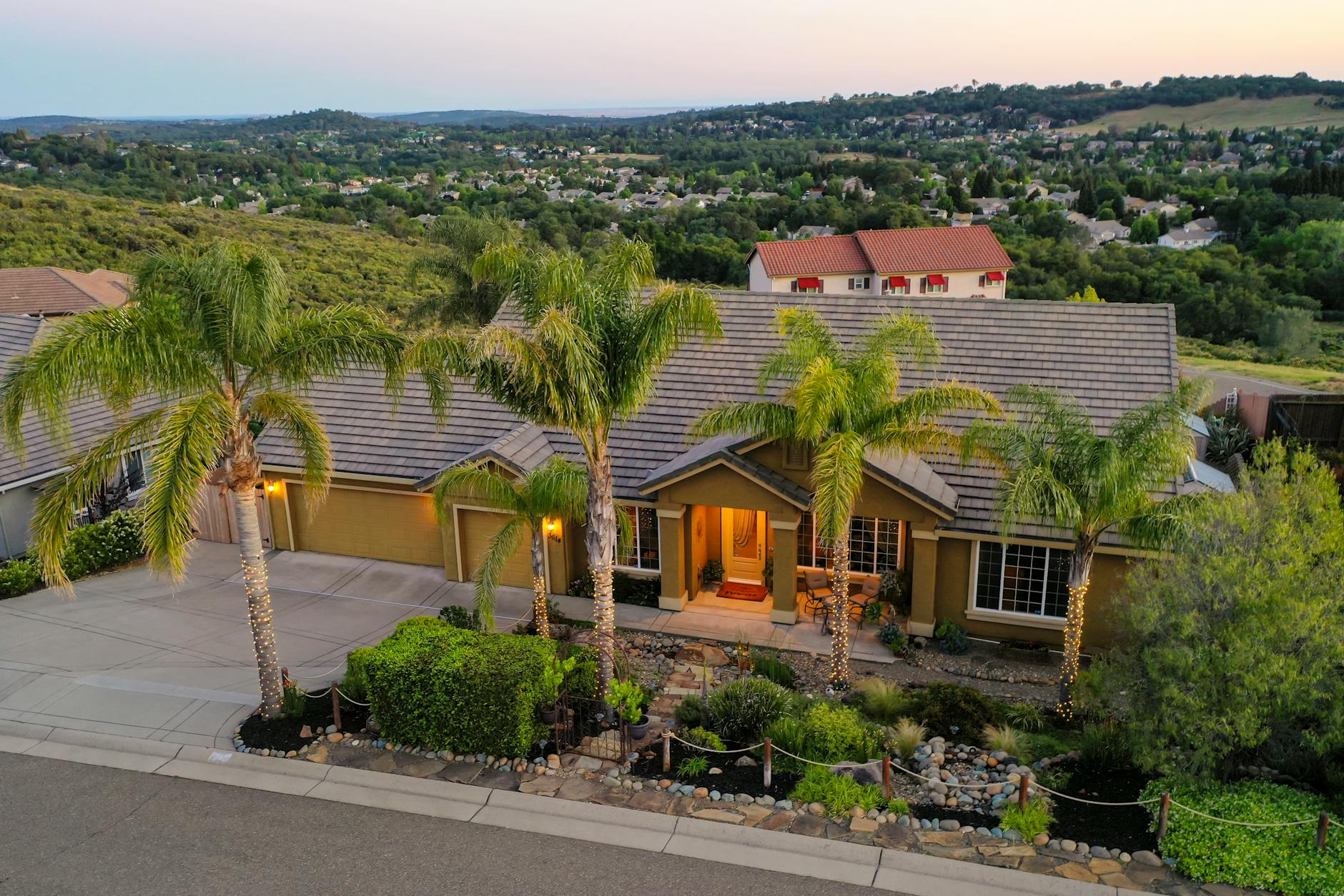 an aerial view of a Newport Beach, California neighborhood featuring residential homes with red tiled roofs, well-maintained gardens, and palm trees
